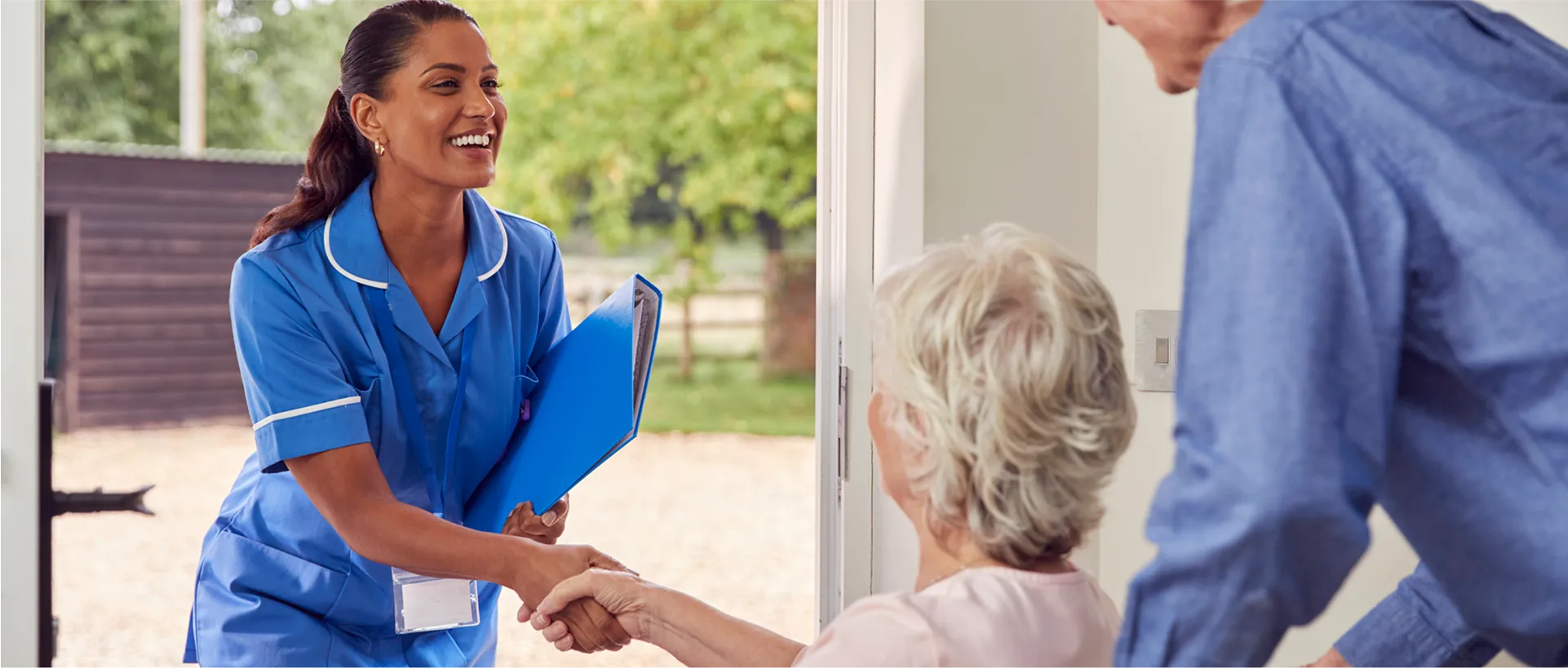 Nurse greeting elderly woman at home.