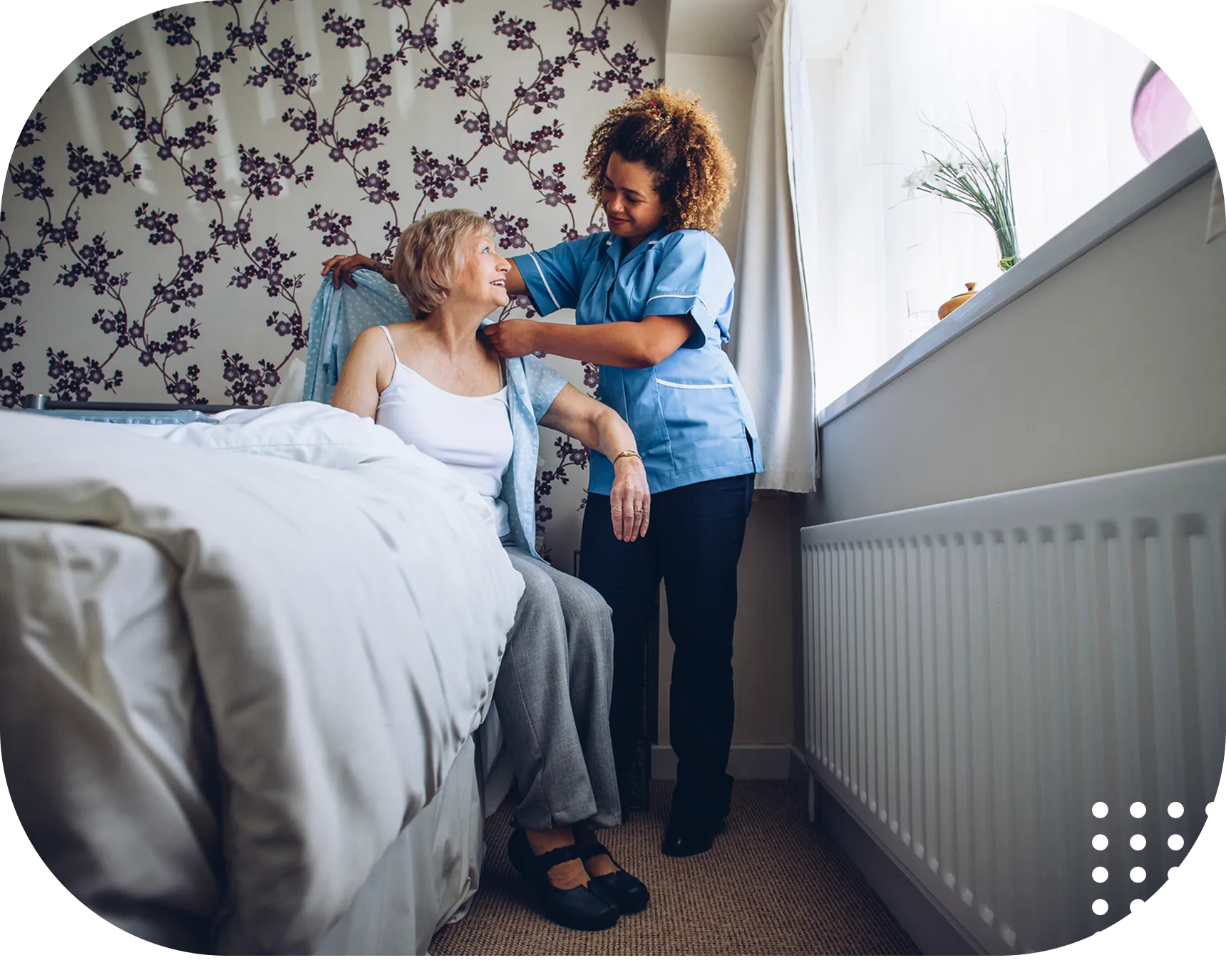 Caregiver assisting elderly woman in bedroom.