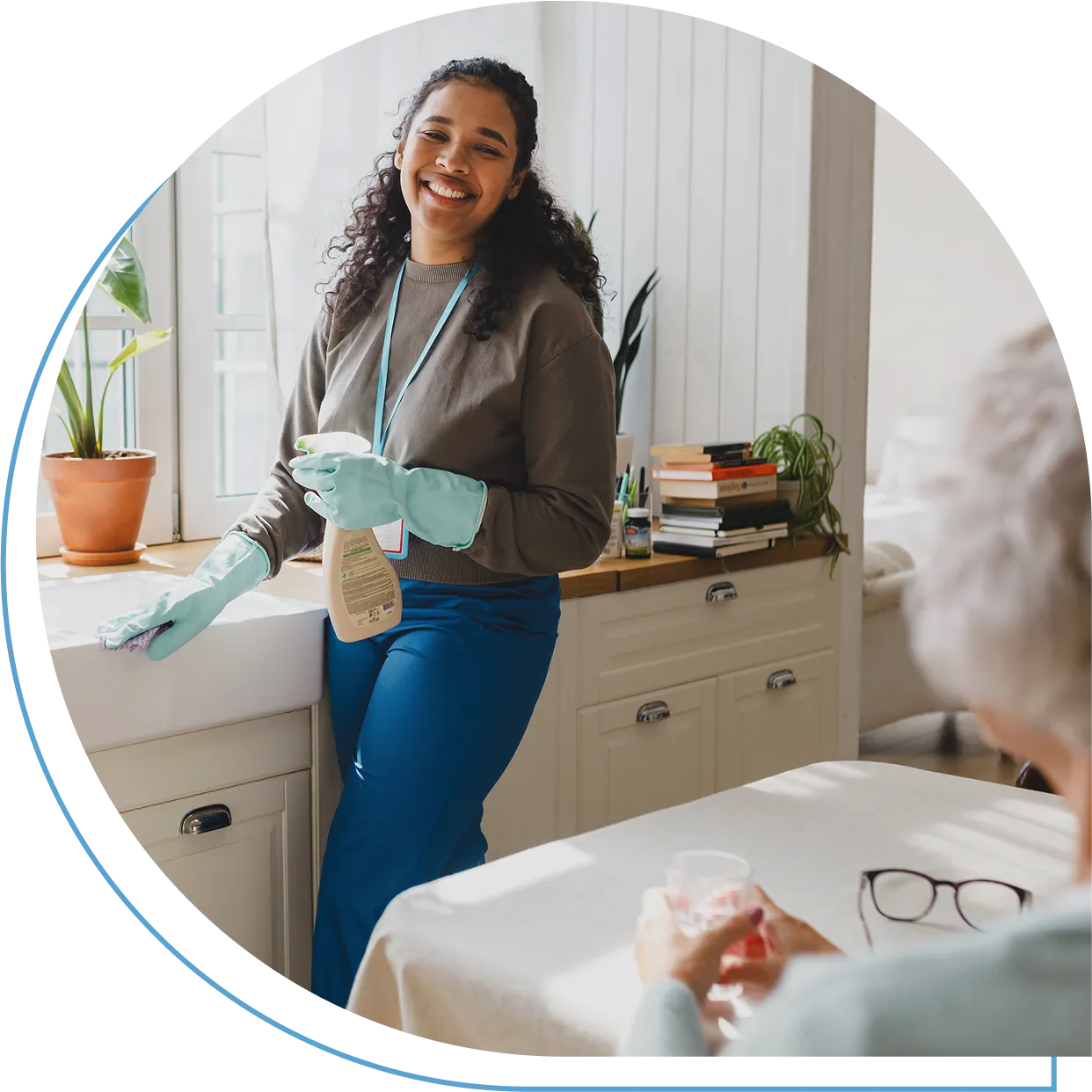 Smiling woman cleaning kitchen, elderly woman seated.