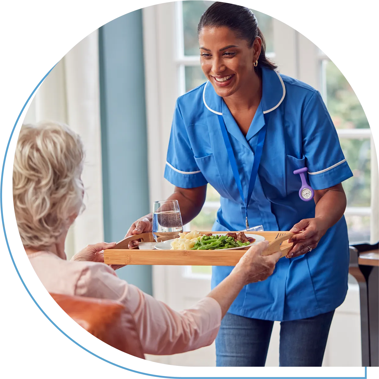 Caregiver serving meal to elderly woman.