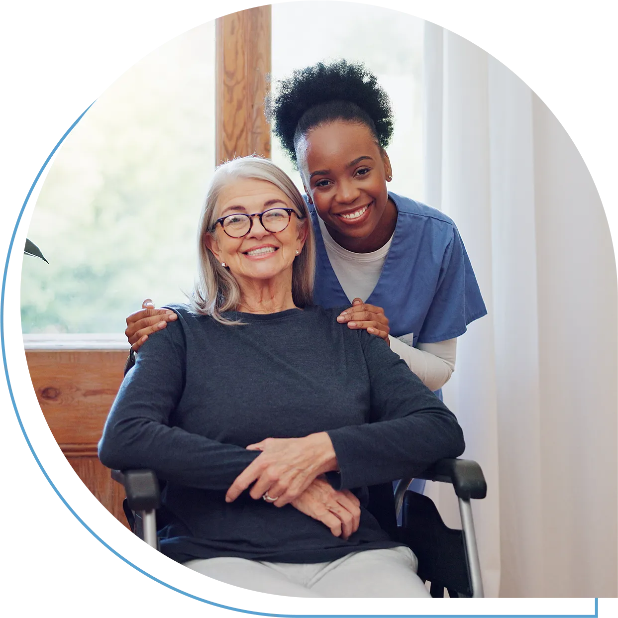 Caregiver smiling with elderly woman in wheelchair.